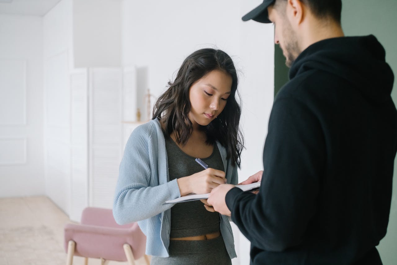 Woman signing for a package delivered by courier at home interior.